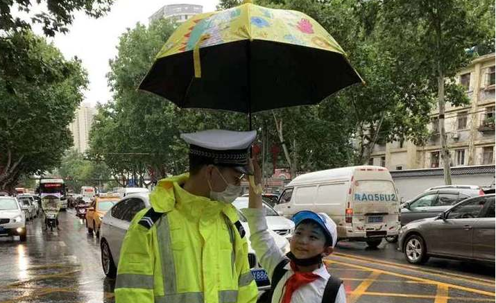暖心！交警冒雨疏导交通 小学生主动帮忙打伞