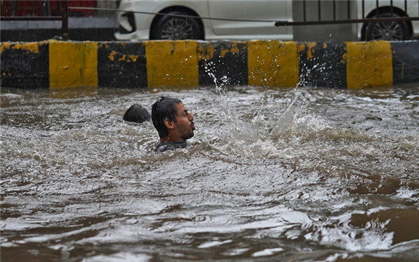 印度多地遭遇暴雨袭击 男子在街道洪水中“游泳”