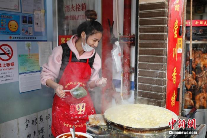 在上海宝山区一个农贸市场里的一家煎饼铺，“煎饼西施”黄璐瑶一边做煎饼，一边上网直播并与网友交流。 殷立勤 摄