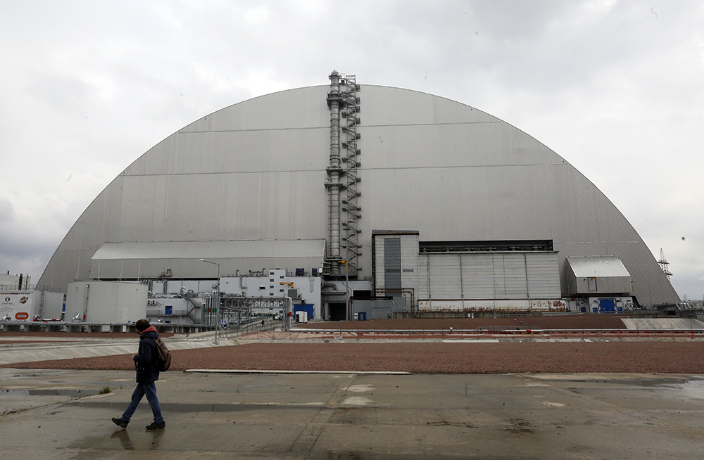 当地时间2021年4月15日，乌克兰切尔诺贝利，一名男子走过被盖住的切尔诺贝利核电站反应堆。人民视觉 图