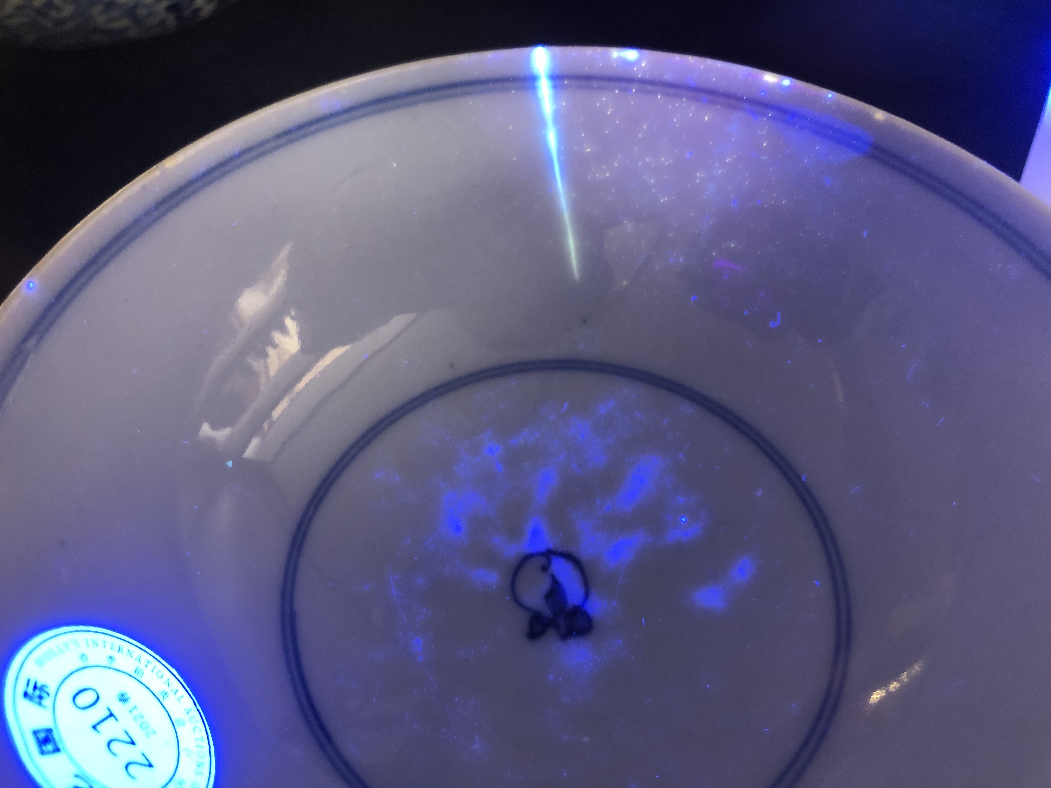 在蓝光灯照射下，牛先生竞买的瓷碗上有裂纹显现。
