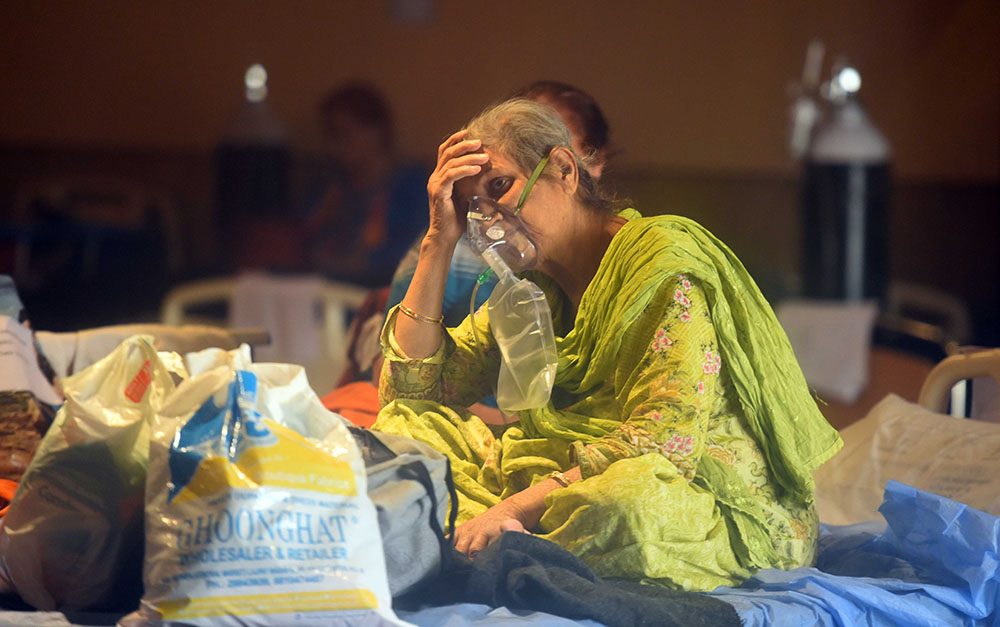 当地时间2021年4月28日，印度新德里，一名妇女坐在医院临时的新冠肺炎护理中心内的病床上吸氧。人民视觉 图