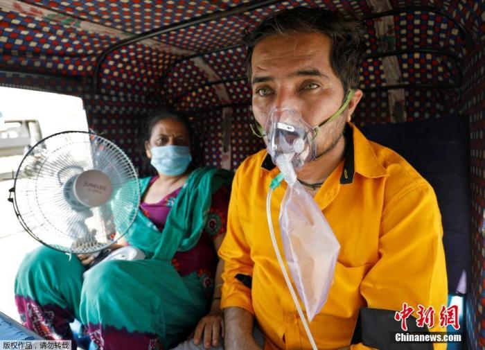当地时间4月25日，一名患者和他的妻子在三轮车内等待进入医院接受治疗。