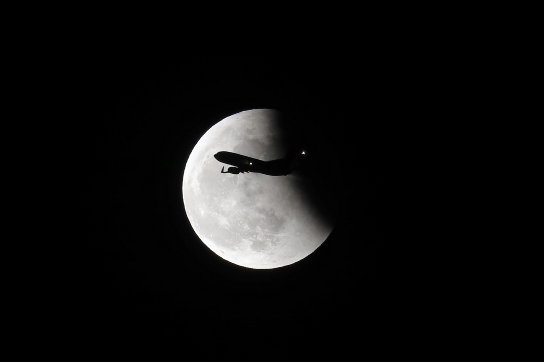 2021年5月26日，北京，一架航班从正在复圆的月亮前飞过。陈维松 图