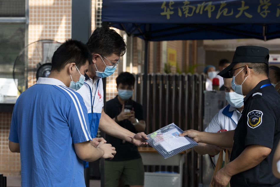 2021年6月7日，广州，华南师范大学附属中学考点，一名视障考生在工作人员带领下，准备进场。据了解，该考生是广州首位使用盲文考卷的考生。他的理想大学是星海音乐学院，已通过了术科考试。
