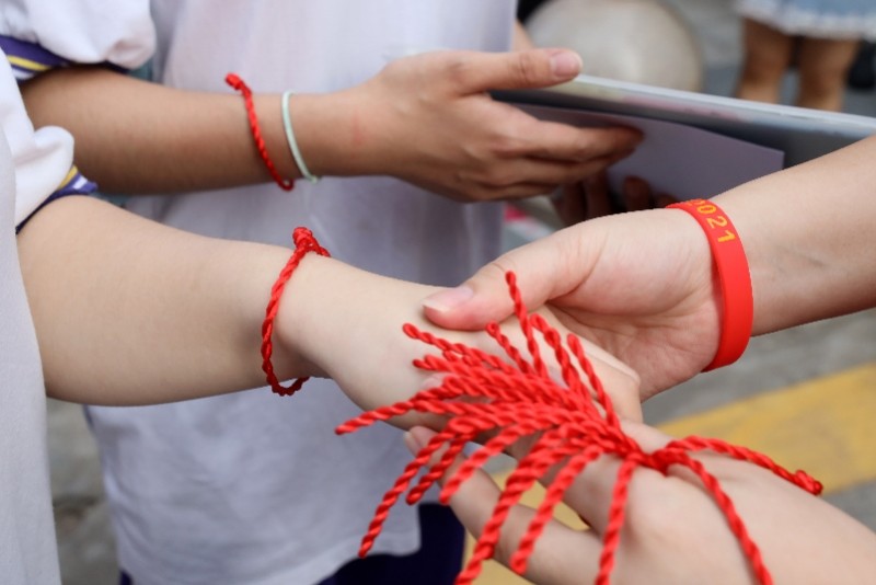 2021年6月7日，广州市育才中学考点，老师将红绳系在考生的手腕上。冯宙锋/南方都市报 图