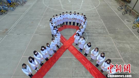  图为大学生们携手“抗艾”，拼大型“红丝带”图案。孟德龙 摄