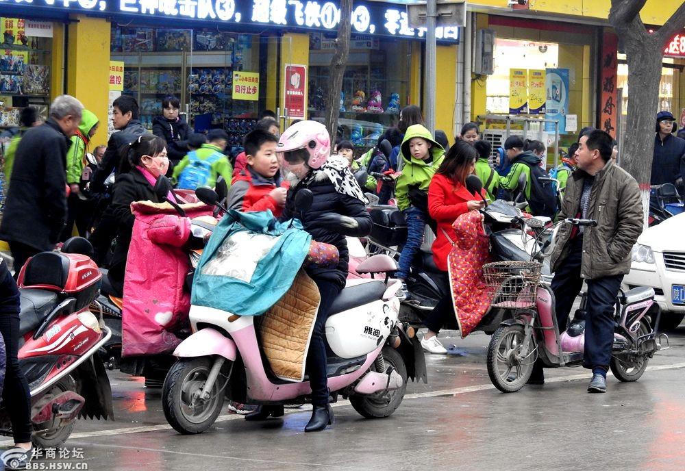 实拍家长阴雨天接放学孩子回家!
