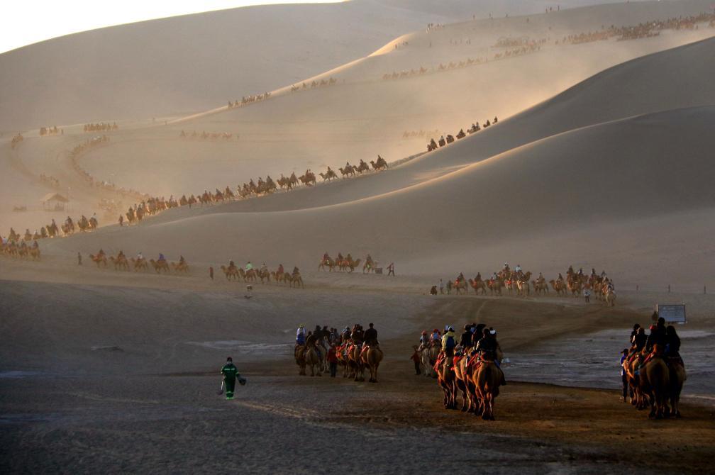 10月2日，游客在甘肃省敦煌市鸣沙山月牙泉景区体验骑骆驼。新华社发（张晓亮 摄）